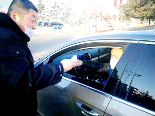 图为东荣二矿保卫科干警严格检查进出矿车辆，对每名进矿职工都进行体温测量并登记。